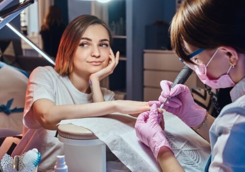 Pretty dreamy woman got nail care from young manicurist.